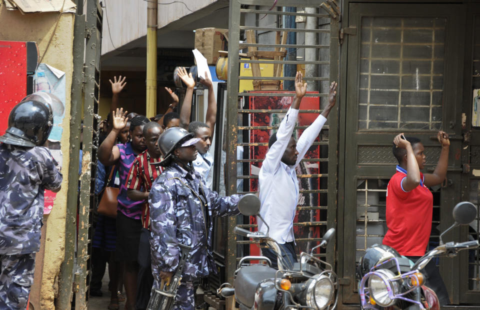 Residents are ordered out of a building with their hands in the air as security forces pursue protesters in Kampala, Uganda Monday, Aug. 20, 2018. Ugandan police fired bullets and tear gas to disperse a crowd of protesters demanding the release of jailed lawmaker, pop star, and government critic Kyagulanyi Ssentamu, whose stage name is Bobi Wine. (AP Photo/Ronald Kabuubi)