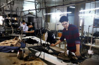 In this July 26, 2018 photo, Afghan musician Mohammad Rezai, right, a member of the Arikayn rock band, works as a tailor in Pakdasht, on the outskirts of Tehran, Iran. The four rockers that make up the band, known as Arikayn, that plays Metallica-inspired ballads are Afghan refugees, and their struggles mirror those of millions of other Afghans who have fled to Iran during decades of war. (AP Photo/Ebrahim Noroozi)