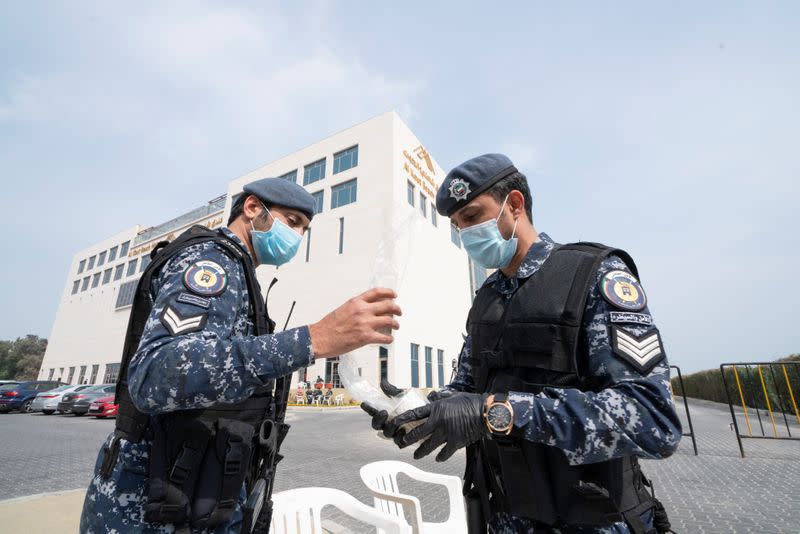 Kuwaiti special forces wearing protective masks are seen at the entrance to a hotel where people evacuated from Iran are being held in quarantine, in Fahaheel