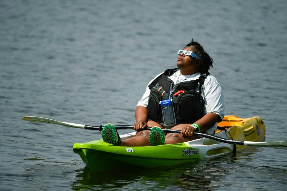 Quianna Poole, 48, of Spartanburg, watches the partial eclipse from a kayak at Lake Cooley Outdoor Education Center in Lyman, S.C., on Monday, April 8, 2024.