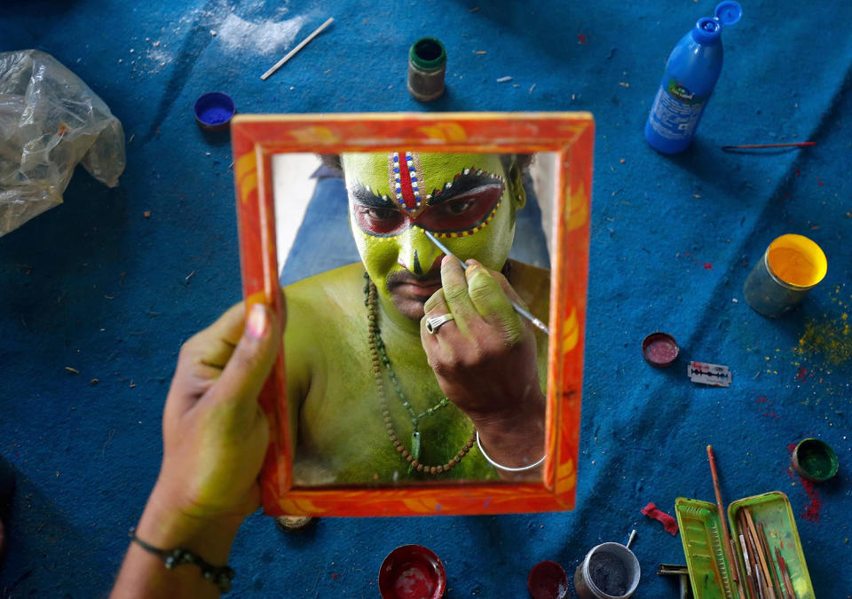 An artiste is reflected in a mirror as he applies make-up backstage in Bengaluru