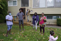 Sophonie Bizimana, center, a permanent U.S. resident who is a refugee from Congo, waves from the steps of his home in Kirkland, Wash., Wednesday, Oct. 14, 2020, as four of his children and a granddaughter look on. Bizimana's wife, Ziporah Nyirahimbya, is in Uganda and has been unable so far to join him in the U.S. For decades, America admitted more refugees annually than all other countries combined, but that reputation has eroded during Donald Trump's presidency as he cut the number of refugees allowed in by more than 80 percent. (AP Photo/Ted S. Warren)