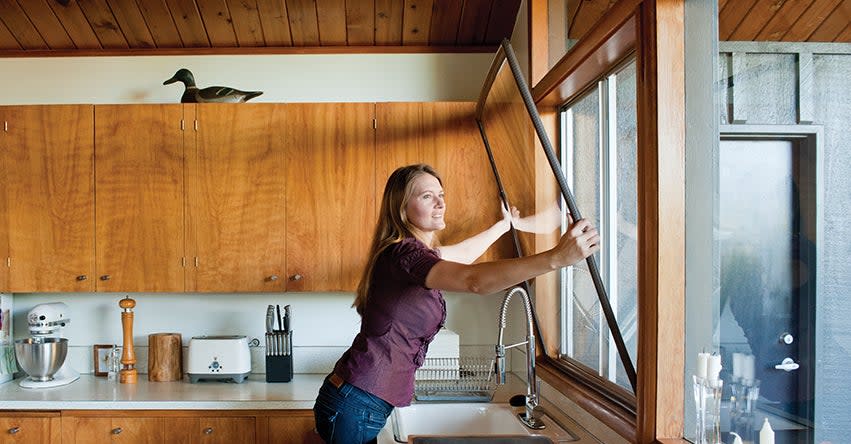 woman installing a window insert into a large kitchen window