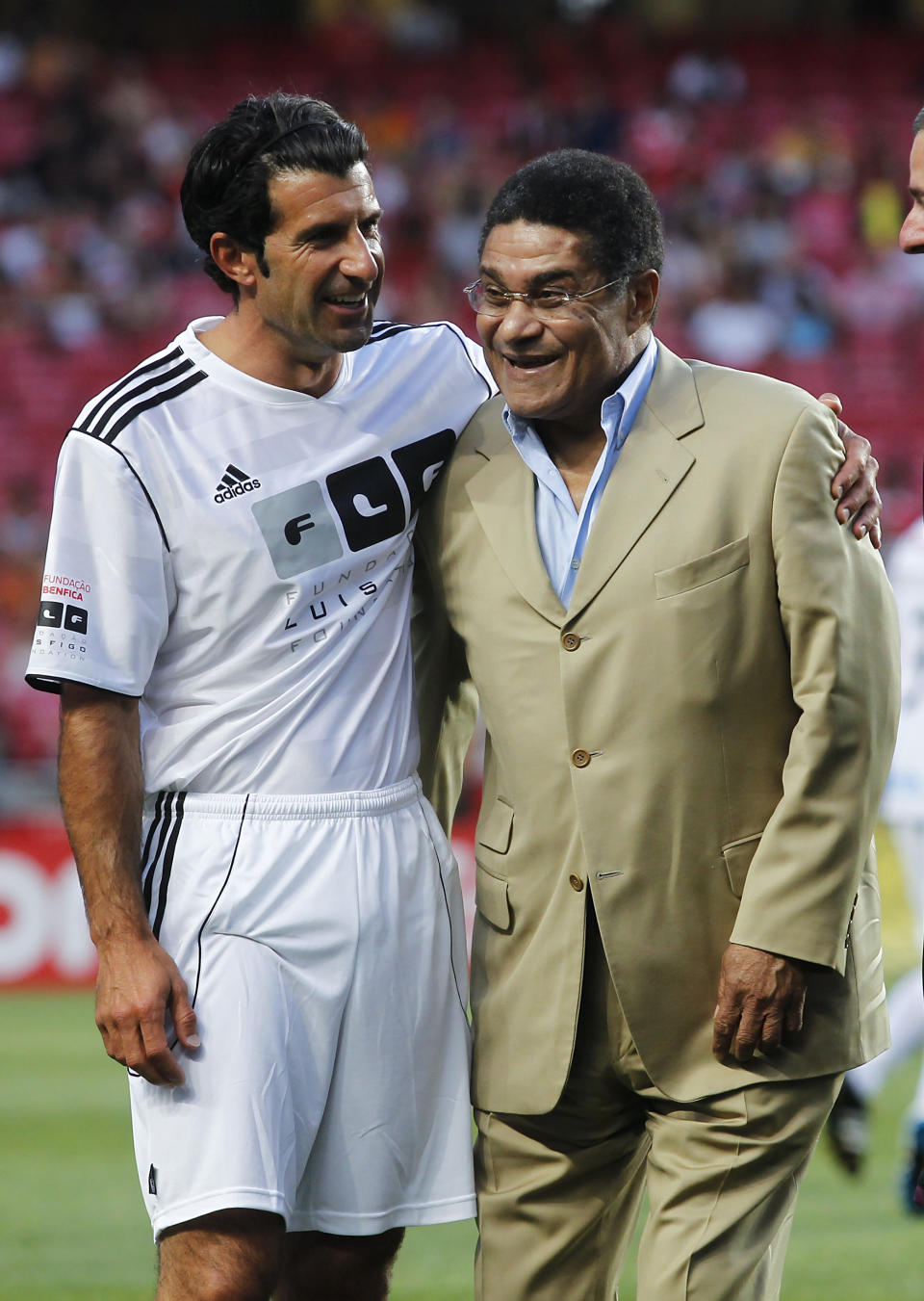 FILE - In this July 18, 2012 file photo, Eusebio embraces Portuguese star player Luis Figo, left, prior to 'An Act Against Hunger' friendly soccer match between Benfica and Luis Figo and the Rest of the World team at Benfica's Luz stadium in Lisbon. Eusebio, the Portuguese football star who was born into poverty in Africa but became an international sporting icon and was voted one of the 10 best players of all time, has died of heart failure aged 71, Sunday, Jan. 5 2014. (AP Photo/Francisco Seco, File)