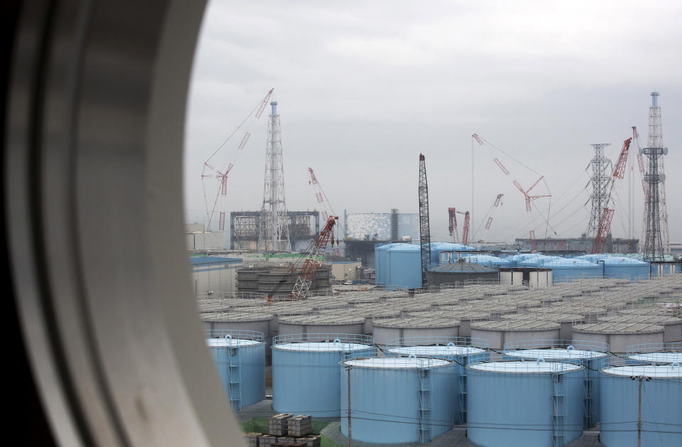 FILE - In this Feb. 23, 2017, file photo, storage tanks for contaminated water are seen through a window of a building during a media tour to the tsunami-crippled Fukushima Dai-ichi nuclear power plant of the Tokyo Electric Power Co. (TEPCO) in Okuma town, Fukushima prefecture. Japan’s economy and industry ministry unveiled a draft revision Monday, Dec. 2, 2019, to its decades-long roadmap to clean up the radioactive mess at the Fukushima nuclear power plant, which was wrecked by a massive earthquake and tsunami in 2011. (Tomohiro Ohsumi/Pool Photo via AP, File)