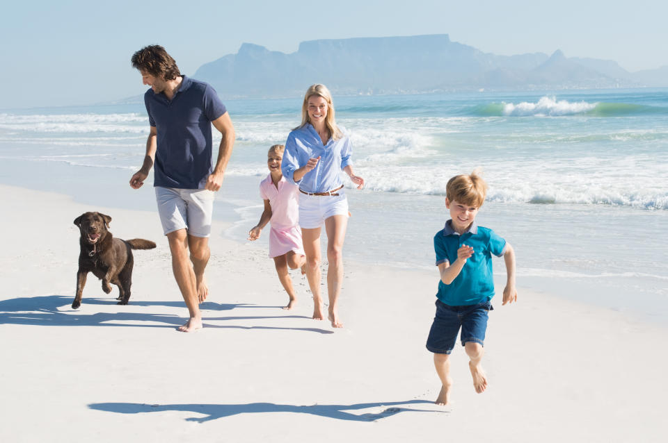 Happy family running at beach with pet dog