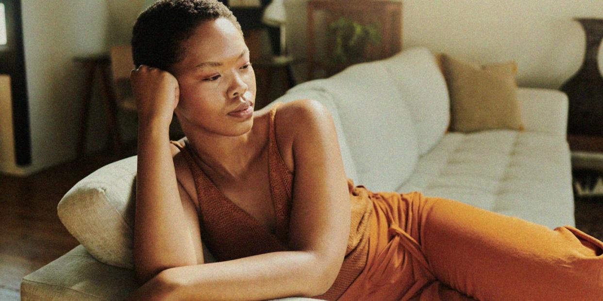 a black woman sitting on a couch looking thoughtful