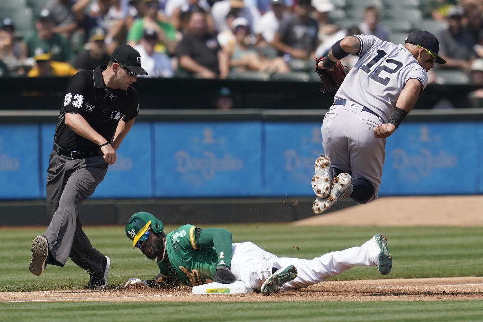 Oakland Athletics' Starling Marte, bottom, steals third base under New York Yankees third baseman Rougned Odor (12) as umpire Will Little (93) watches during the third inning of a baseball game in Oakland, Calif., Saturday, Aug. 28, 2021. (AP Photo/Jeff Chiu)