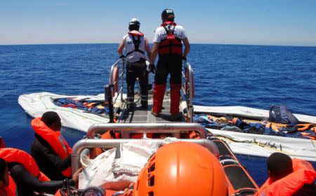 Nick Romaniuk (L) and Max Avis of the NGO SOS Mediterranee take a last look at a rubber boat that they destroyed so that it cannot be used again by people smugglers off the coast of Western Libya May 18, 2017. Picture taken May 18, 2017. REUTERS/Steve Scherer