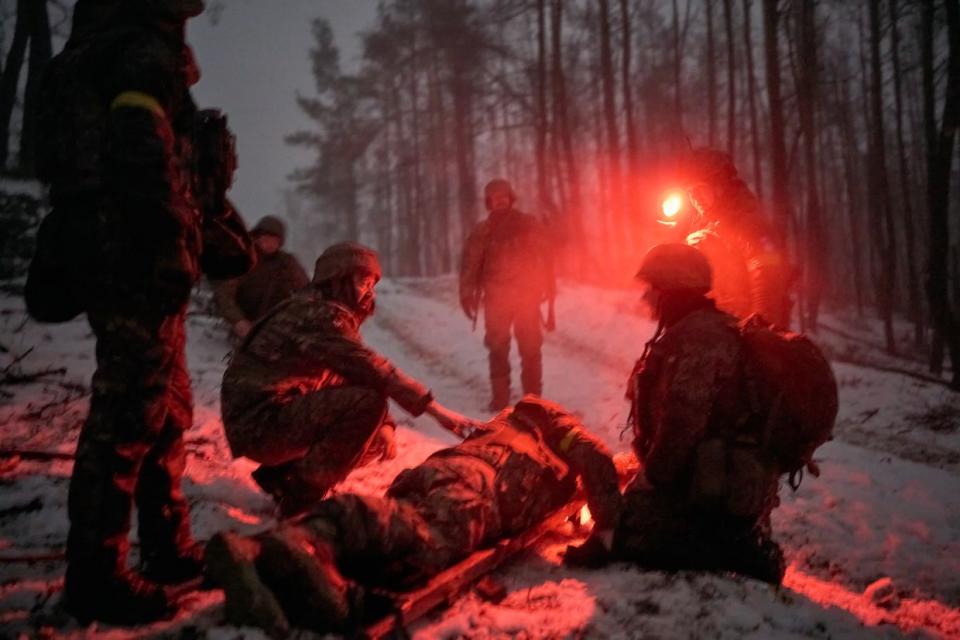 Medics evacuate a wounded soldier who tripped on a petal mine as evacuation takes place in darkness in the middle of a damaged forest in Kupiansk frontline, Ukraine on Jan. 27, 2024. (Kostiantyn Liberov/Libkos/Getty Images)