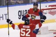 Florida Panthers defenseman MacKenzie Weegar (52) congratulates center Joe Thornton after Thornton scored a goal during the first period of an NHL hockey game against the Washington Capitals, Tuesday, Nov. 30, 2021, in Sunrise, Fla. (AP Photo/Wilfredo Lee)