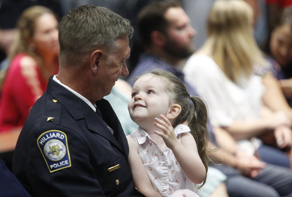 Ivy Clark, 3, looks up at her grandfather, Hilliard Police Lt. Ron Clark, as she sits on his lap prior to the ceremony where he was sworn in as deputy chief.