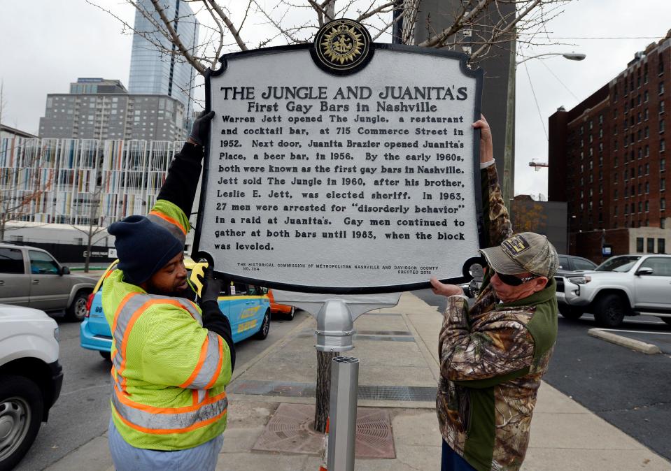 On Tuesday, December 4, 2018, in Nashville, Tennessee, Metro Nashville Public Works workers Lorenzo Jackson and James Gentry, Sr. install the new Jungle and Juanita historic marker along Commerce Street.  The designation signifies that these were the first gay bars in Nashville.