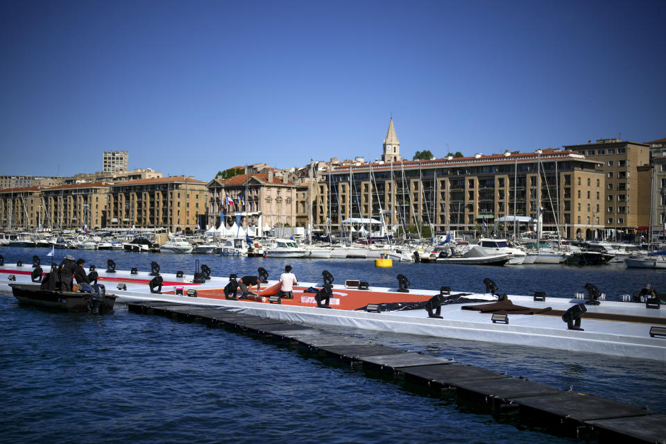 Workers prepare a stage for the arrival of the Olympic flame in the Old Port of Marseille in southern France, Tuesday, May 7, 2024. The Olympic torch will finally enter France when it reaches the southern seaport of Marseille on Wednesday. (AP Photo/Daniel Cole)