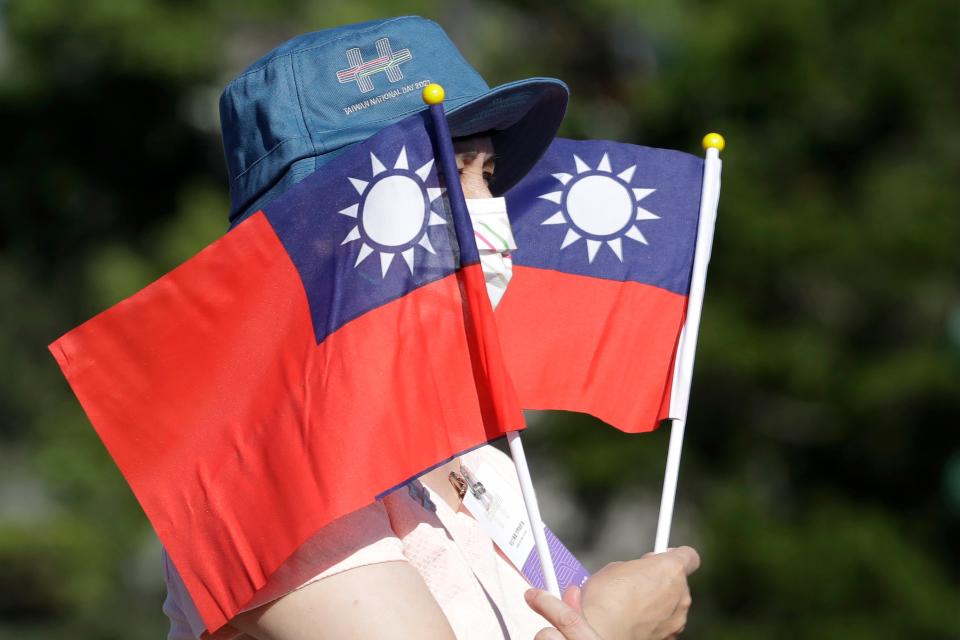 A woman holds up Taiwan national flags during National Day celebrations in front of the Presidential Building in Taipei, Taiwan.  In 1997, Beijing grumbled but swallowed its irritation when then-Speaker Newt Gingrich of the U.S. House of Representatives visited Taiwan.   A quarter-century later, news reports that the current speaker, Nancy Pelosi, might visit Taiwan, Beijing is warning of “forceful measures” including military action if she does.