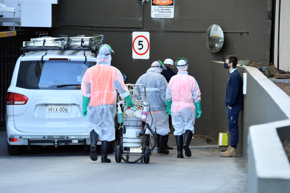 Cleaners in HAZMAT suits arrive at a locked downed apartment building on Devitt Street in the suburb of Blacktown in Sydney. Source: AAP