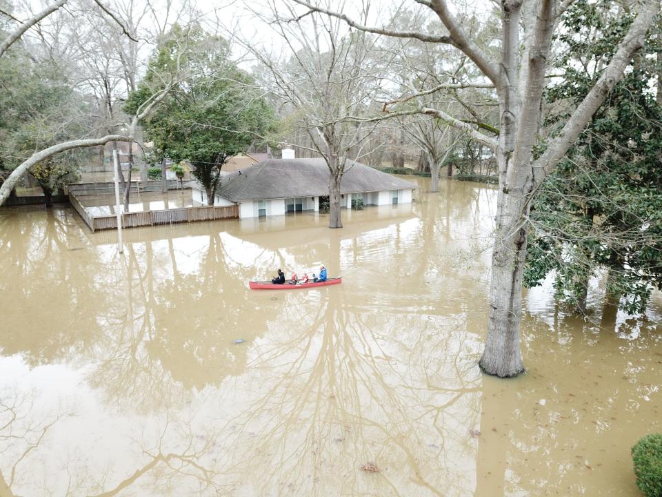 Nate Green, his two children and Clarion Ledger reporter Wilton Jackson canoe through Jackson streets during severe flooding on Sunday, Feb. 16, 2020.