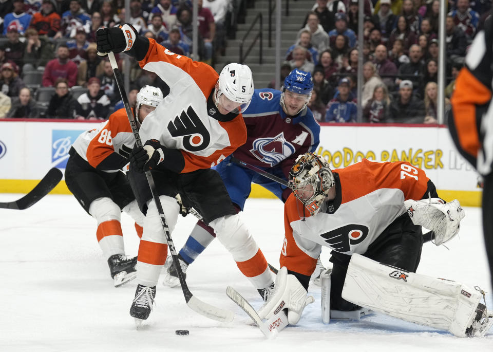 Philadelphia Flyers defenseman Egor Zamula, front left, clears the puck after a save by Flyers goaltender Carter Hart, right, on a shot by Colorado Avalanche right wing Mikko Rantanen (96) in the first period of an NHL hockey game Saturday, Dec. 9, 2023, in Denver. (AP Photo/David Zalubowski)