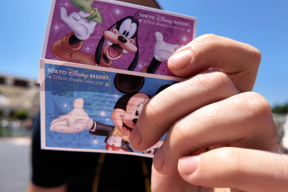 Shane Hryhorec holding up his Tokyo Disney tickets to the camera.