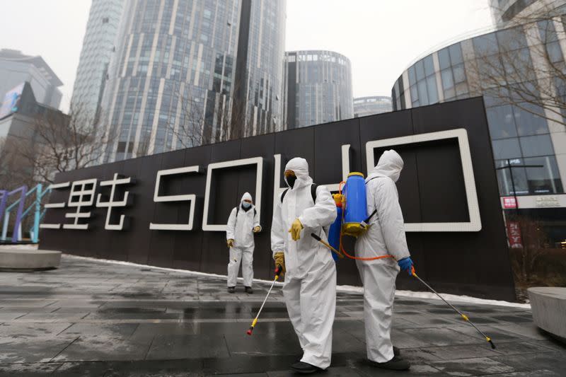 Workers in protective suits disinfect a commercial complex with sanitizing equipment, following an outbreak of the novel coronavirus in the country, in Beijing