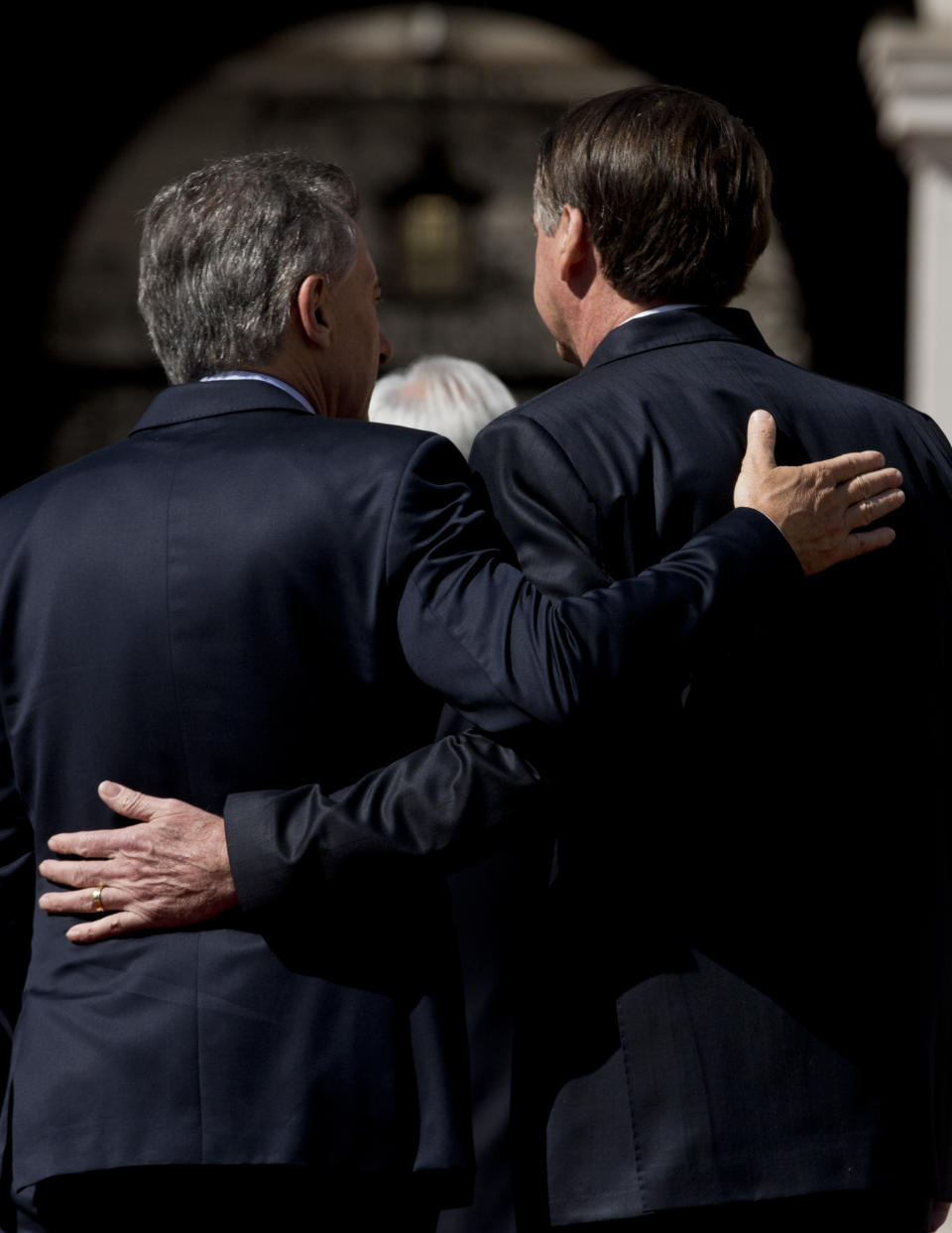 Argentina's President Mauricio Macri, left, and Brazil's President Jair Bolsonaro, walk arm in arm after posing for an official group photo, outside La Moneda presidential palace in Santiago, Chile, Friday, March 22, 2019. South American heads of state are meeting in Santiago to discuss the development of a new regional political bloc called Prosur, the idea being to replace the Unasur, the current body that many describe as defunct. (AP Photo/Esteban Felix)