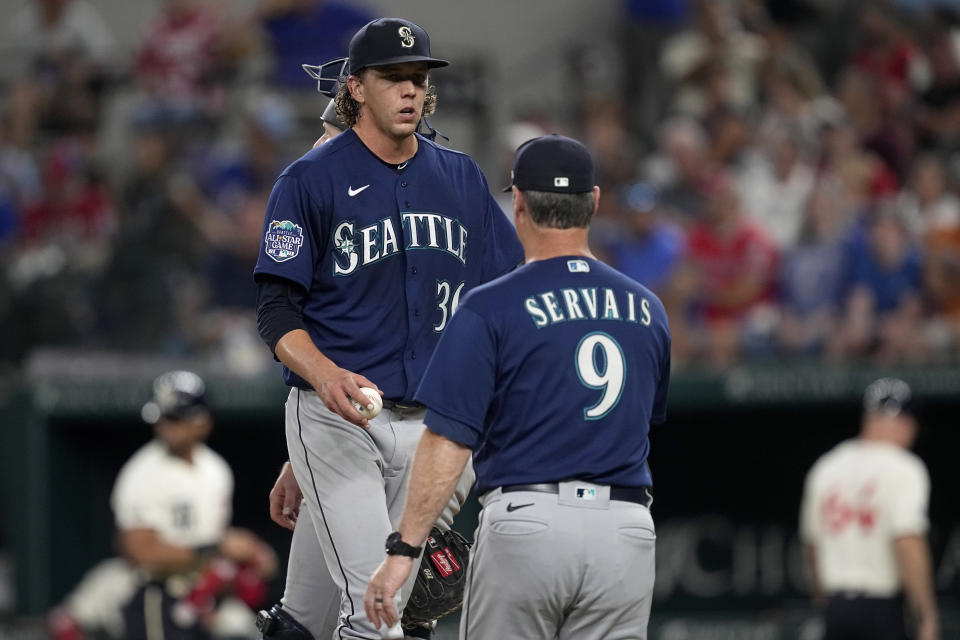 Seattle Mariners starting pitcher Logan Gilbert, left, turns the ball over to manager Scott Servais (9) in the sixth inning of a baseball game against the Texas Rangers, Saturday, Sept. 23, 2023, in Arlington, Texas. (AP Photo/Tony Gutierrez)