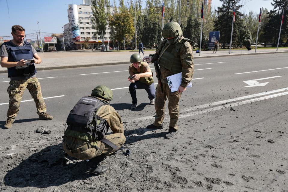 Investigators work at the site of a burning vehicle after shelling in Donetsk, area controlled by Russian-backed separatist forces, eastern Ukraine, Saturday, Sept. 17, 2022. A Ukrainian shelling attack killed four people in downtown Donetsk on Saturday. According to the city's Mayor Alexey Kulemzin, fragments of munitions for Caesar howitzers were found. (AP Photo/Alexei Alexandrov)