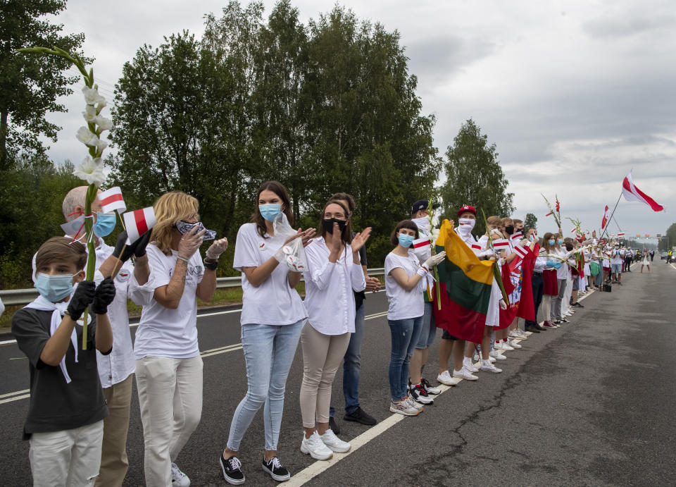 Supporters of Belarus opposition from Lithuania hold and wave historical Belarusian flags during the "Freedom Way", a human chain of about 50,000 strong from Vilnius to the Belarusian border, during a protest near Medininkai, Lithuanian-Belarusian border crossing east of Vilnius, Lithuania, Sunday, Aug. 23, 2020. In Aug. 23, 1989, around 2 million Lithuanians, Latvians, and Estonians joined forces in a living 600 km (375 mile) long human chain Baltic Way, thus demonstrating their desire to be free. Now, Lithuania is expressing solidarity with the people of Belarus, who are fighting for freedom today. (AP Photo/Mindaugas Kulbis)
