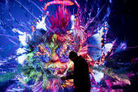 A man walks in front of a screen with a artificial intelligence generated artwork by media artist Refik Anadol, inside the Congress Center where the World Economic Forum take place in Davos, Switzerland, Sunday, Jan. 14, 2024. The annual meeting of the World Economic Forum is taking place in Davos from Jan. 15 until Jan. 19, 2024. (AP Photo/Markus Schreiber)