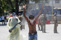 A Sri Lankan police officer disinfects a homeless man before transporting him to an isolation center as a measure to prevent the spread of the new coronavirus during a lockdown in Colombo, Sri Lanka, Friday, April 17, 2020. Sri Lankan authorities claim they have largely managed to prevent community spreading through proper identification and isolation of people who came into contact with COVID-19 patients. (AP Photo/Eranga Jayawardena)