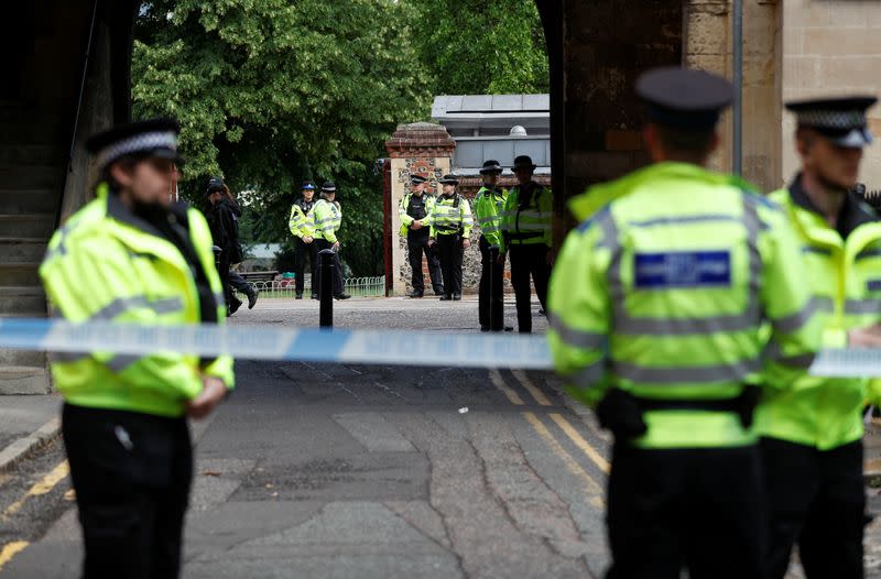Police officers stand behind the cordon at the scene of multiple stabbings in Reading