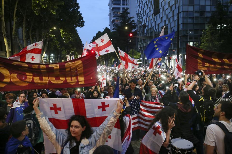 Demonstrators with Georgian national, U.S. and EU flags rally during an opposition protest against the foreign influence bill and celebrating of the Independence Day in the center of in Tbilisi, Georgia, Sunday, May 26, 2024. The opposition has denounced the bill as "the Russian law," because Moscow uses similar legislation to crack down on independent news media, nonprofits and activists critical of the Kremlin. (AP Photo/Zurab Tsertsvadze)