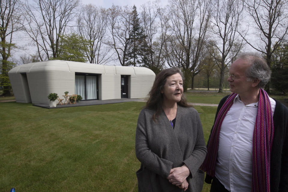 Tenants Elize Lutz, left, and Harrie Dekkers' new home is a 94-square meters (1,011-square feet) two-bedroom bungalow resembling a boulder with windows in Eindhoven, Netherlands, Friday, April 30, 2021. The fluid, curving lines of its gray walls look natural. But they are actually at the cutting edge of housing construction in the Netherlands and around the world. They were 3D printed at a nearby factory. (AP Photo/Peter Dejong)