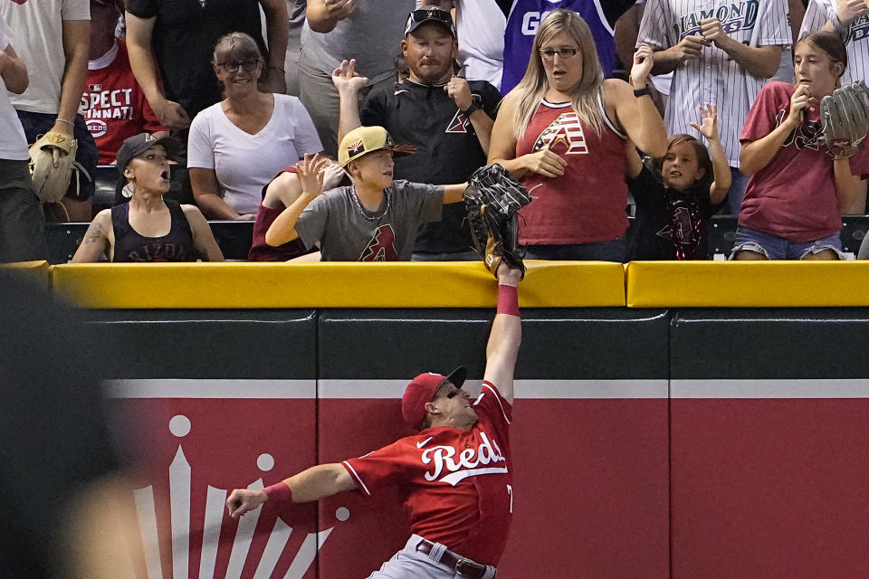 A young fan pulls the ball out of the glove of Cincinnati Reds' Spencer Steer on a ball hit by Arizona Diamondbacks' Tommy Pham during the seventh inning of a baseball game, Friday, Aug. 25, 2023, in Phoenix. The Fan was called for interference on the play and was ejected from the ballpark. (AP Photo/Matt York)