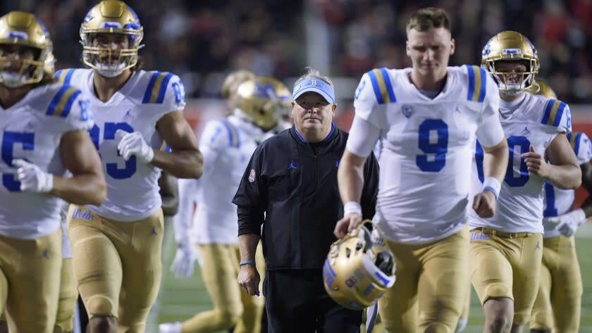 UCLA coach Chip Kelly runs off the field with the team at the end of the first half against Utah