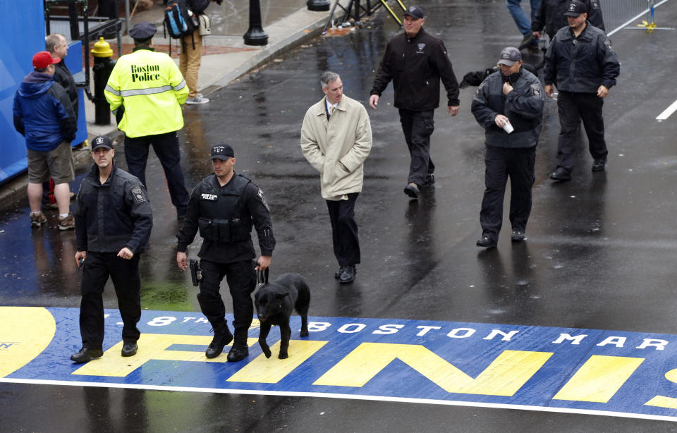 Security personnel walk across the Boston Marathon finish line prior to a remembrance ceremony for family members and survivors of the 2013 Boston Marathon bombing, on Boylston Street in Boston, Tuesday, April 15, 2014. (AP Photo/Elise Amendola)