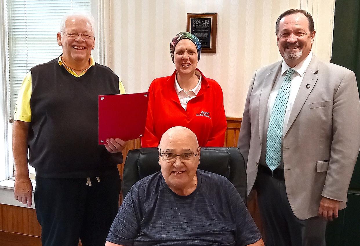 Commissioner Joe Miller (left) presents a proclamation to Cheryl Seabright honoring her as Silver Sneakers Instructor of the Year, as Commissioners Dave Hall (right) and Ray Eyler join the celebration.
