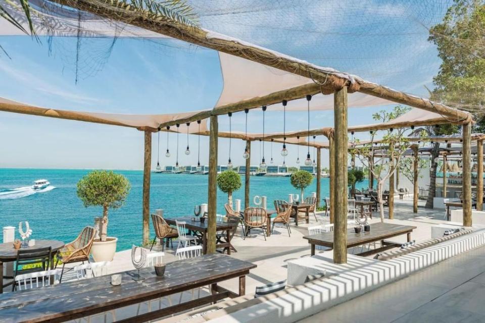 a patio with tables and chairs by the water