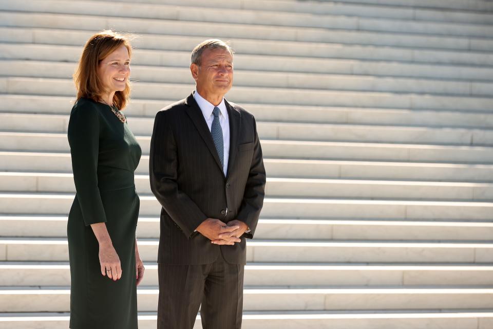 Associate Justice Amy Coney Barrett and Chief Justice John Roberts pause for photographs in the plaza on the west side of the Supreme Court following her investiture ceremony on October 01, 2021, in Washington, D.C. Barrett has been a member of the court for more than a year but her investiture ceremony was delayed because of the coronavirus pandemic.