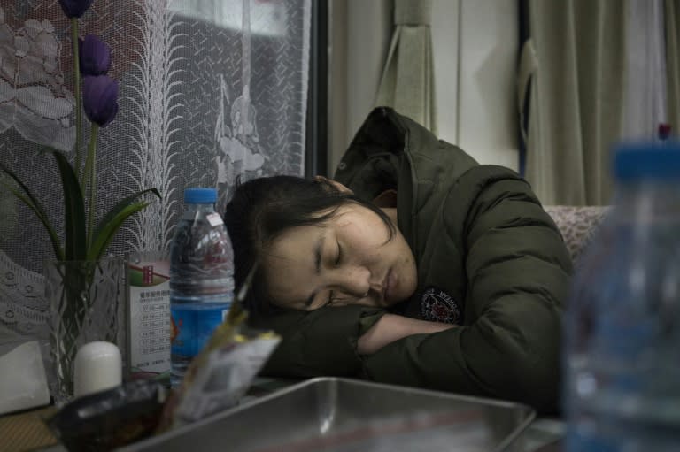 People sleep in the restaurant car during the train journey from Beijing to Chengdu, as travellers head home from the capital ahead of the Lunar New Year