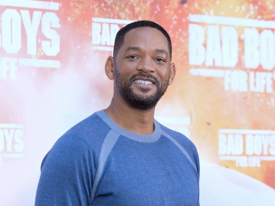 will smith wearing blue shirt and smiling on red carpet