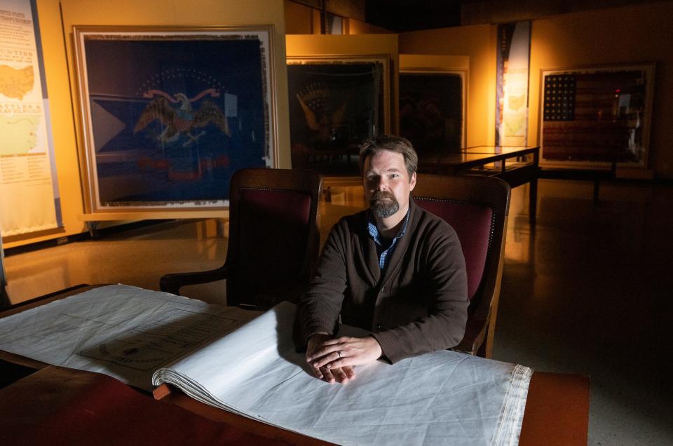 Ben Baughman, a curator for the Ohio History Connection, sits in an exhibit of Ohio battle flags from the Civil War era. Battle flags were used by military regiments for unit cohesion and as a symbol of regimental pride.