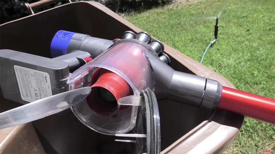 Screenshot of Dyson cleaning tutorial shows opened machine on outdoor bin