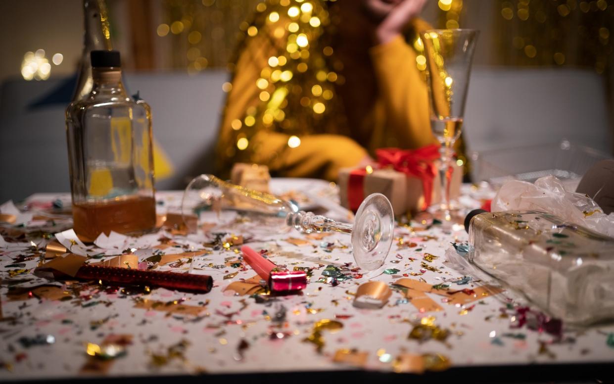 A messy table is covered in confetti, bottles and glasses after a party