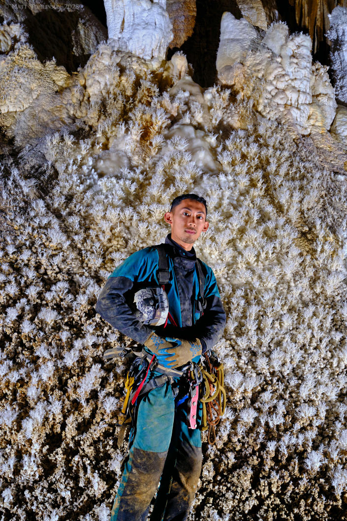 A man stands in front of helictite bushes