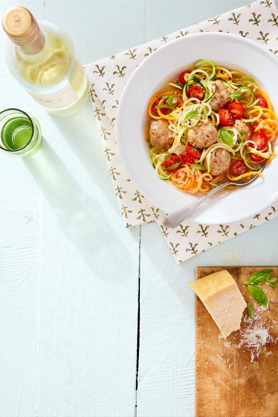 chicken meatball and vegetable noodle soup in a bowl with fresh basil leaves