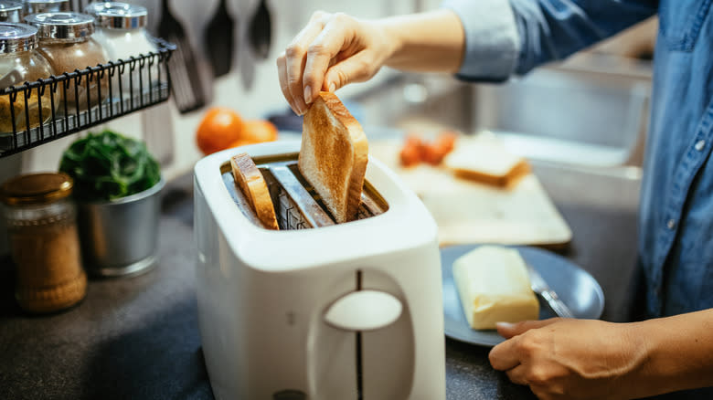 person pulling bread from toaster
