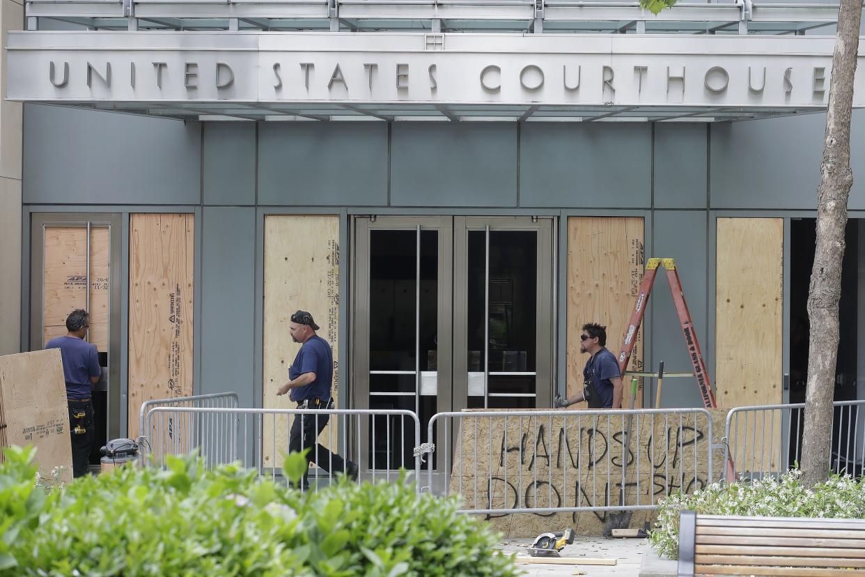 People work outside of a United States Courthouse at the Ronald V. Dellums Federal Building after protests over the death of George Floyd in Oakland, Calif., Saturday, May 30, 2020. 