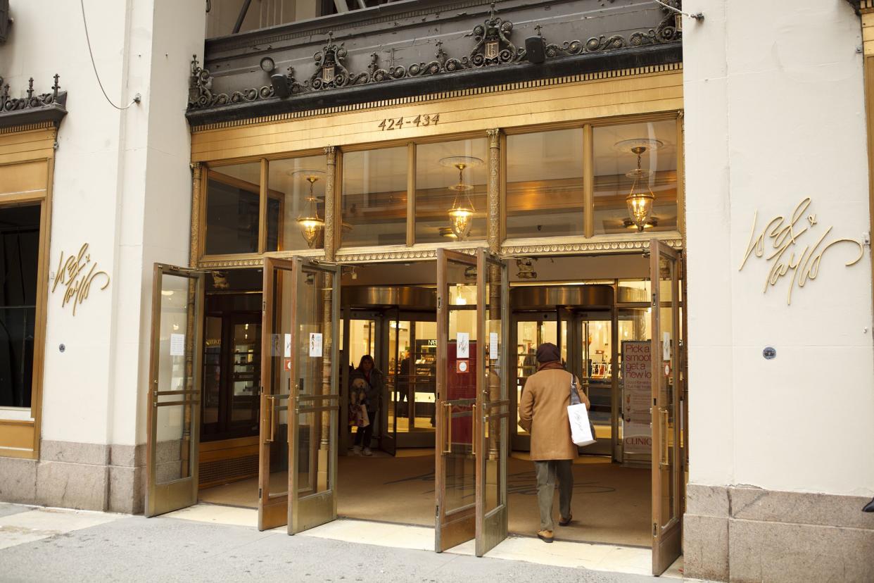 Woman walking through the front doors of the Lord & Taylor flagship department store on Fifth Avenue in Manhattan, New York City, 2011, gold doors and white building