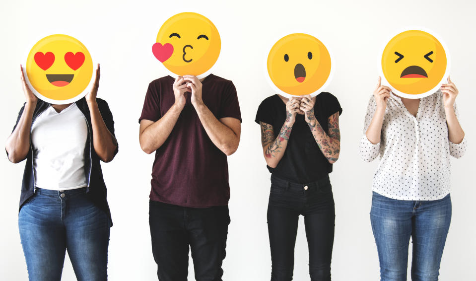 Four people holding common emojis over their faces.